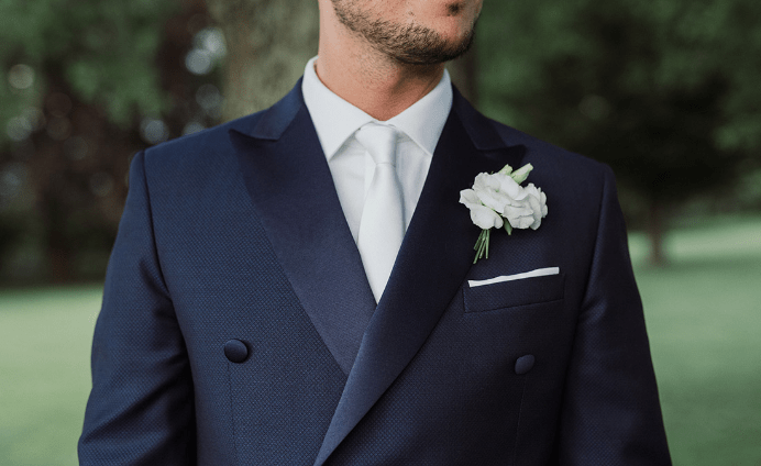 Italian groom wearing a blue suit with a white flower.