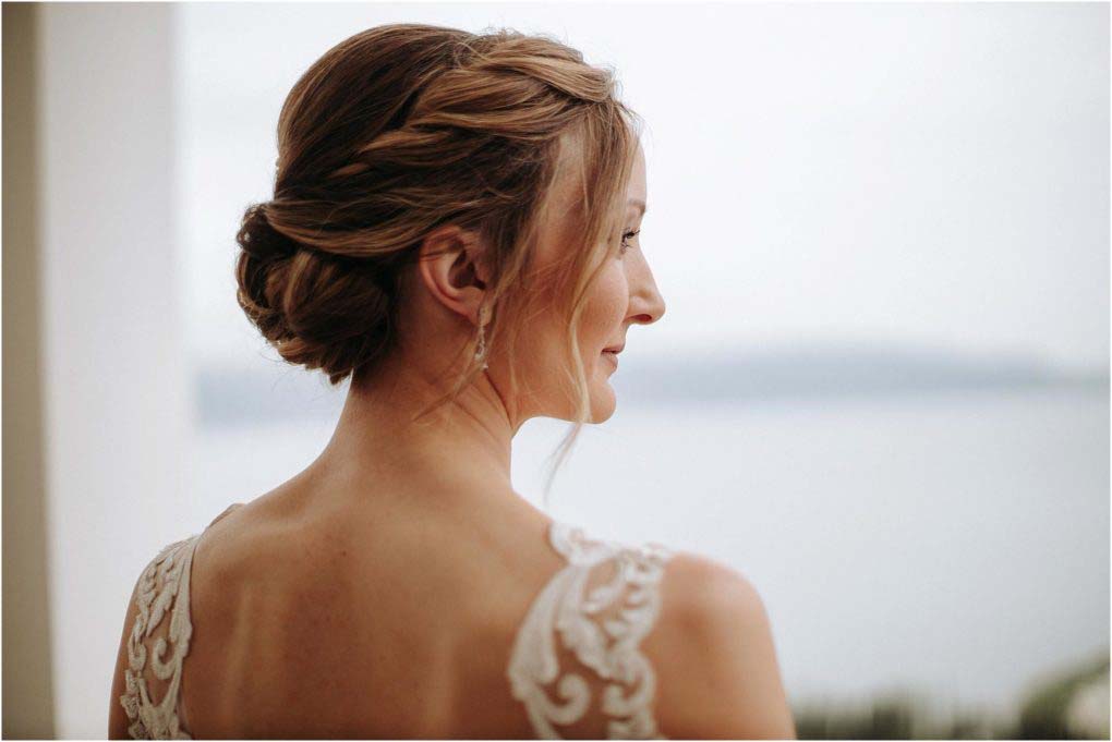 Italian bride with braided hair overlooking the sea on her wedding day.