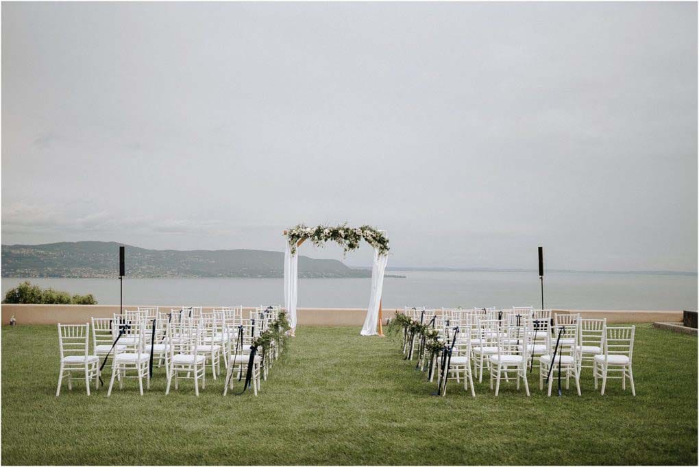Italian wedding on Garda Lake, with white chairs all facing the wedding arbor.