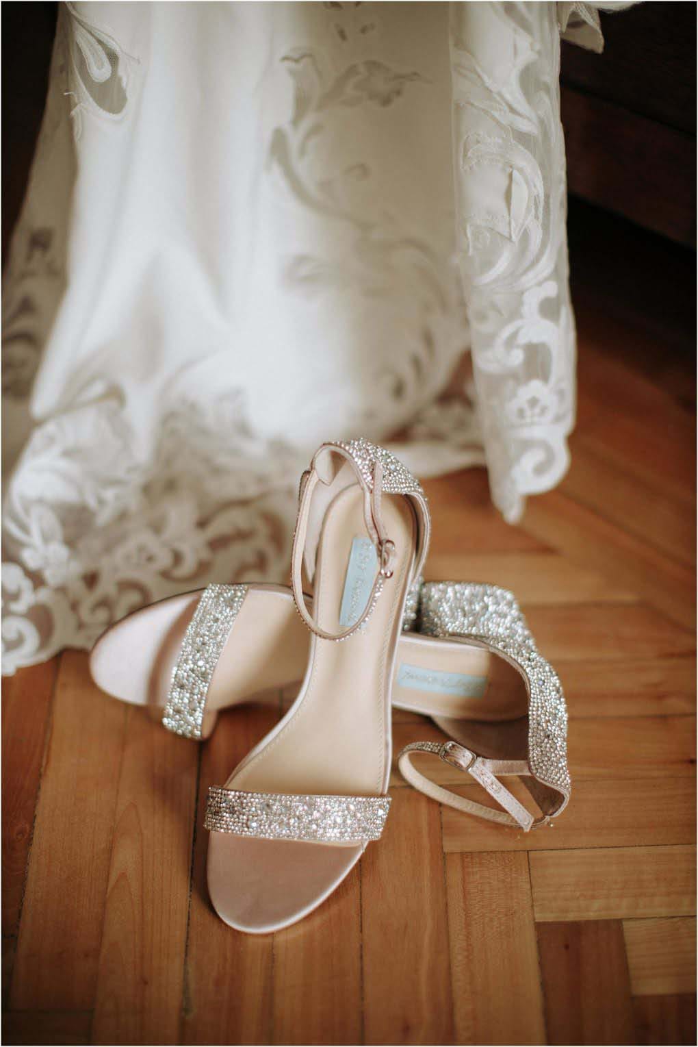 The brides lace gown hangs with her crystal encrusted shoes below.