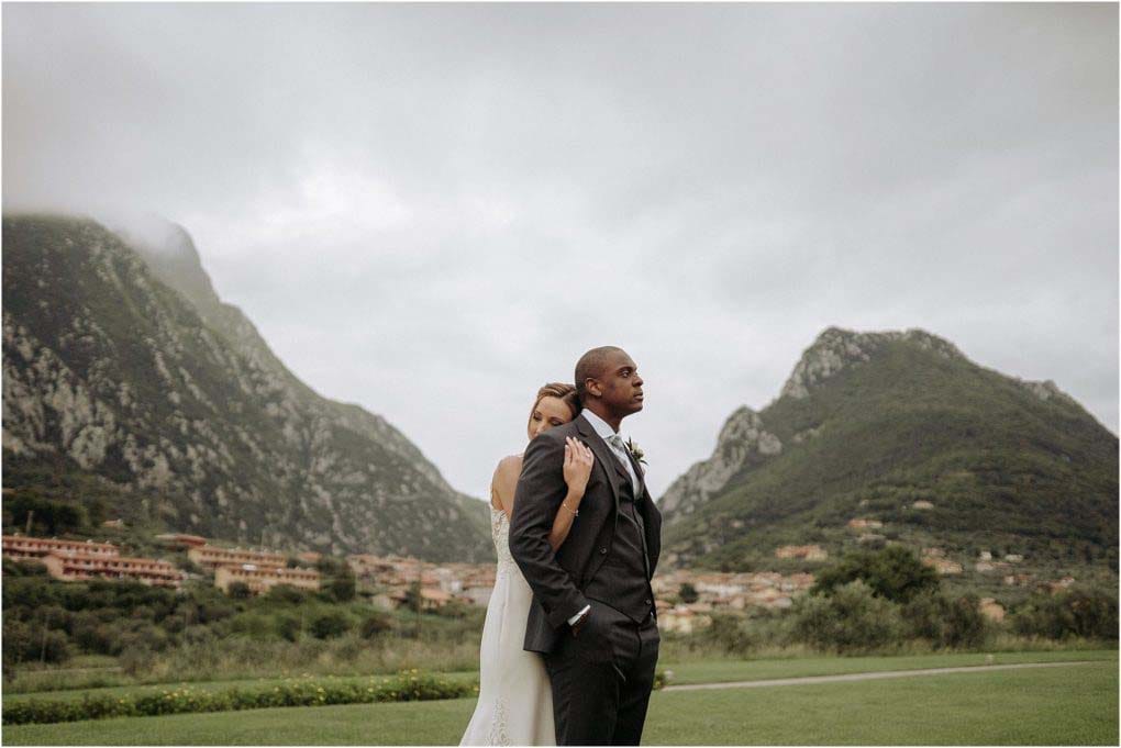 Bride and Groom embrace with the Italian mountains in the background.