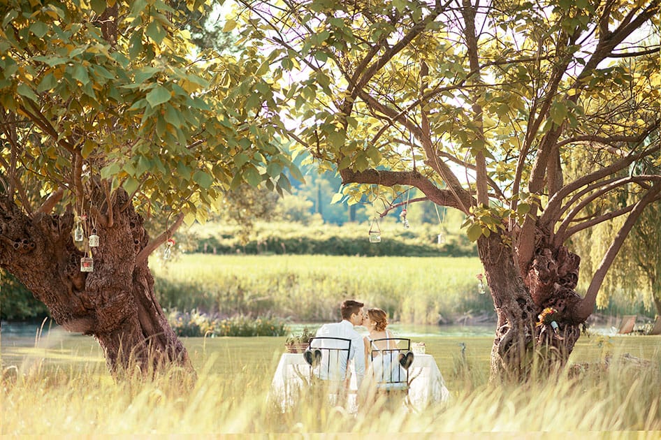 Bride and groom kiss under the trees overlooking the lake.