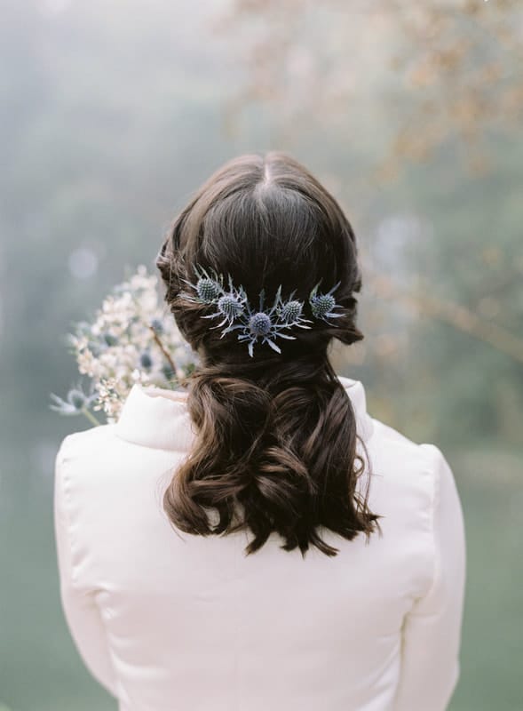 A winter bride with dark hair and blue thistle in her hair.